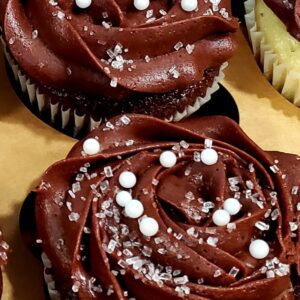 A close up of two cupcakes with chocolate frosting.