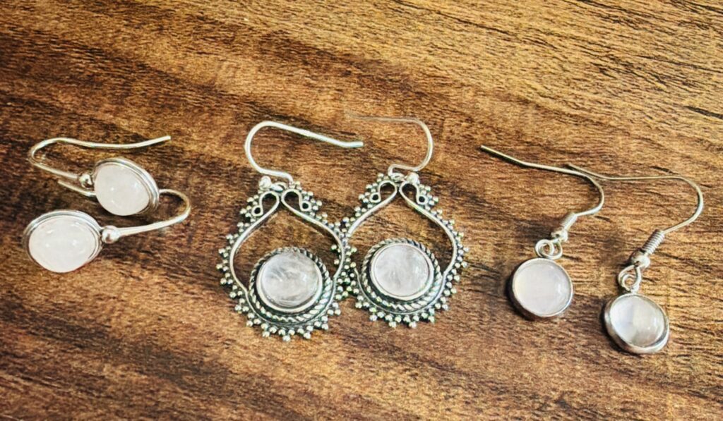 Three pairs of silver earrings on wood.