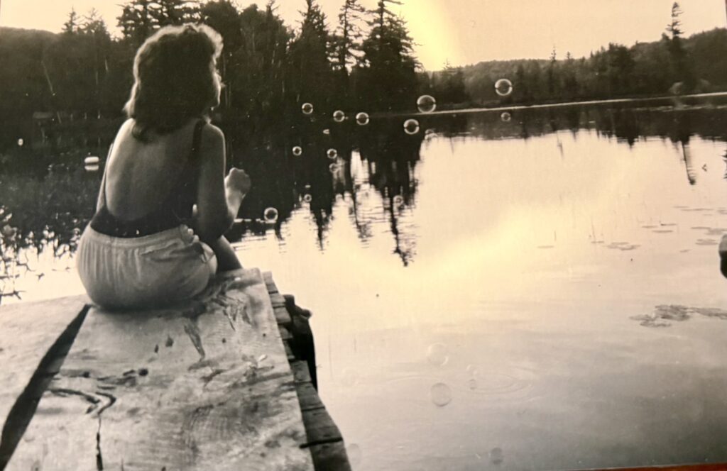 Woman sitting on dock blowing bubbles.