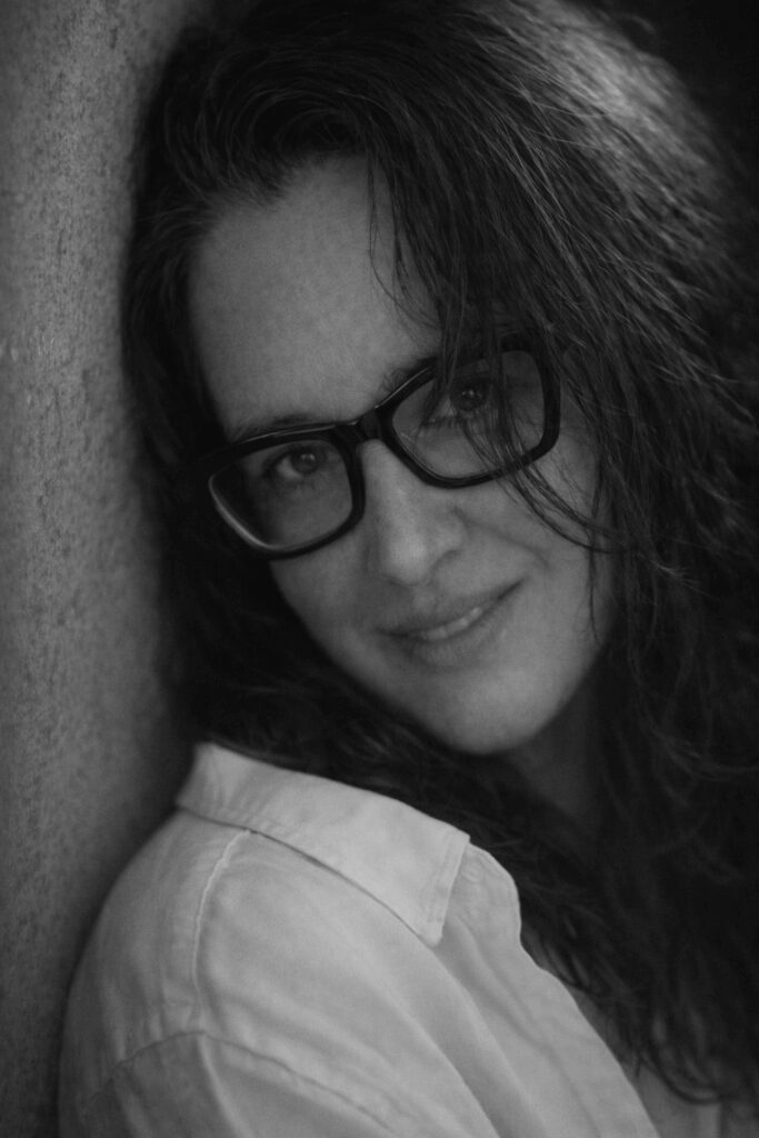 Woman with glasses, smiling in black and white.