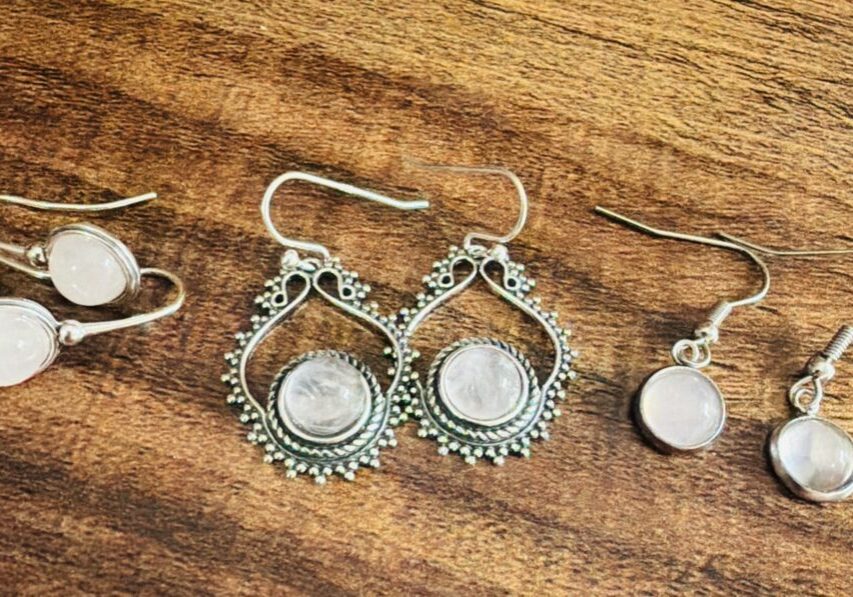 Three pairs of silver earrings on wood.